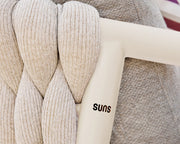 Textile braided chair with 'suns' branding on a blurred outdoor background
