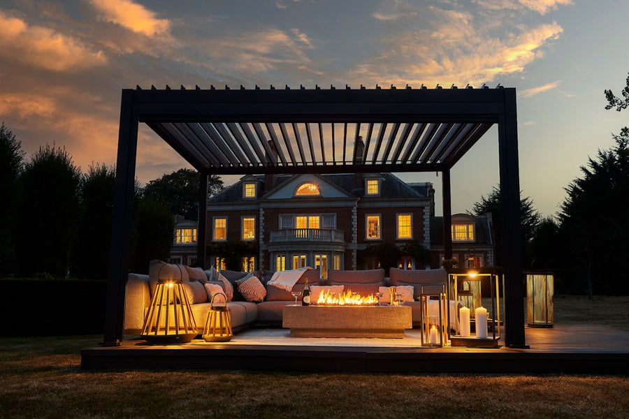 Luxe pergola lit up at dusk outside a large home