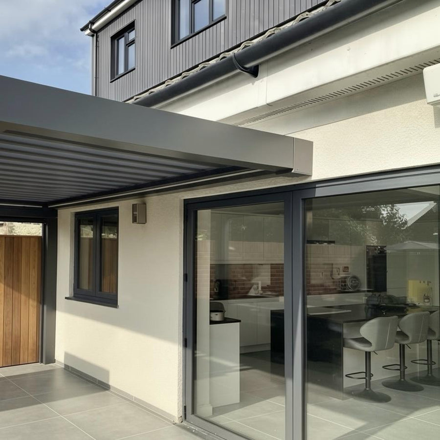 Grey Luxe pergola wall-mounted to the back of a house over bifold doors